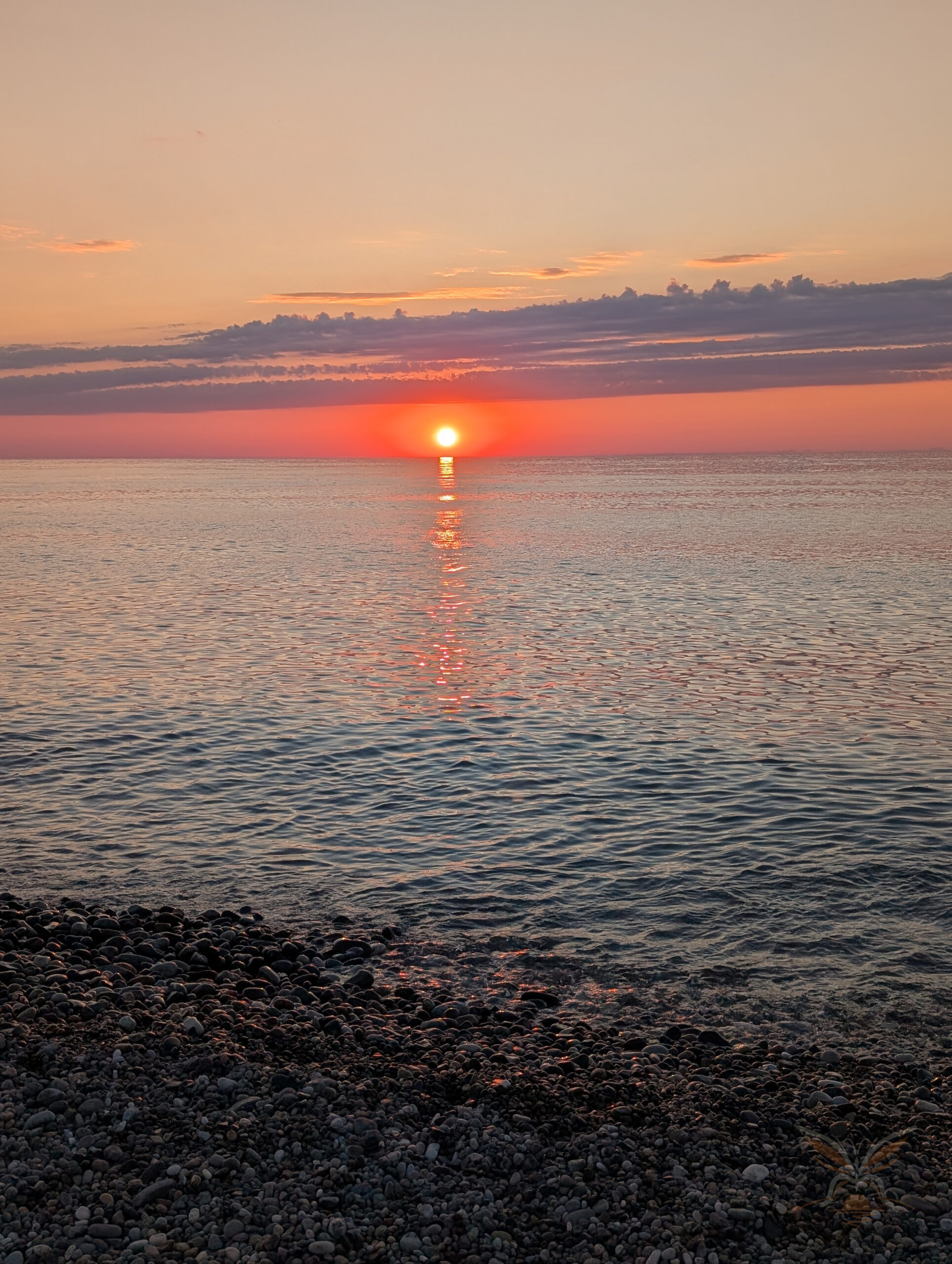 Sunset over the Black Sea with a pebbled shore in Batumi, Georgia.