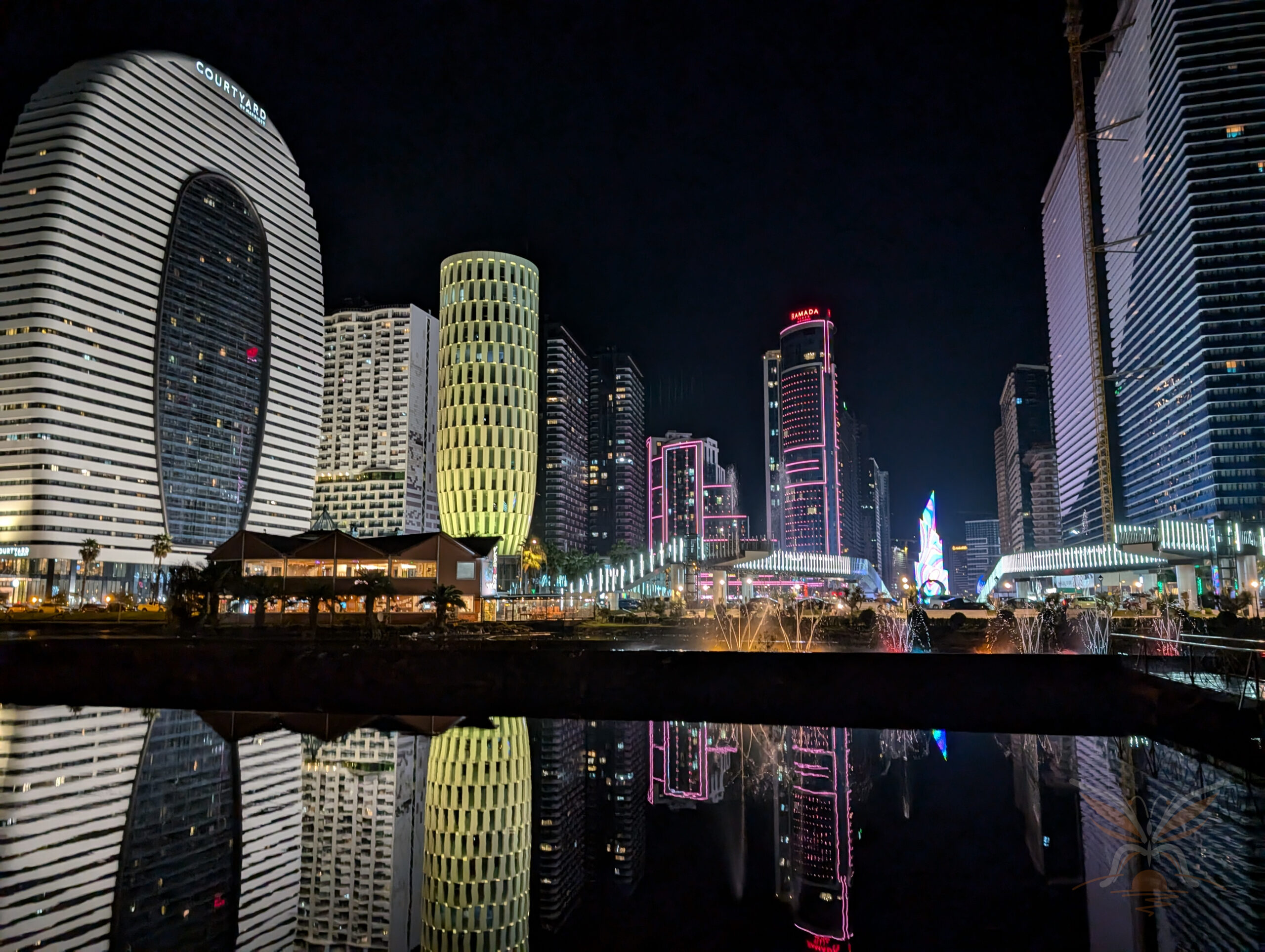 Illuminated Batumi skyline and dancing fountains reflected in Ardagani Lake at night.