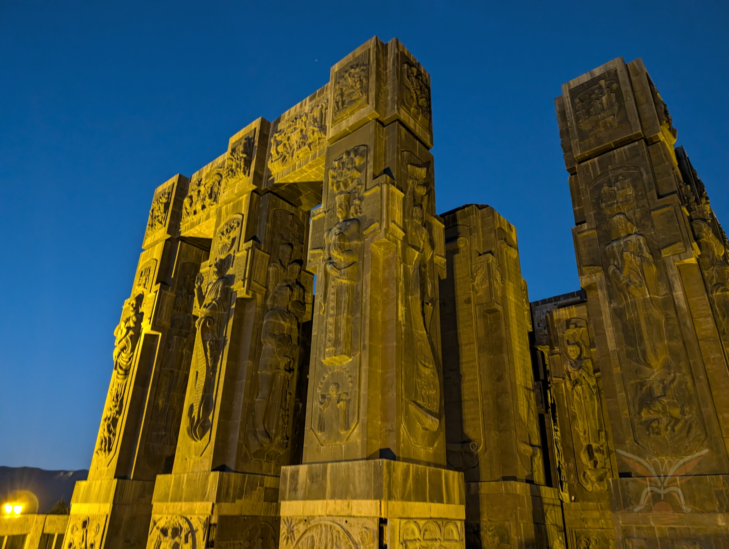 Illuminated relief-covered pillars of the Chronicles of Georgia monument in Tbilisi.