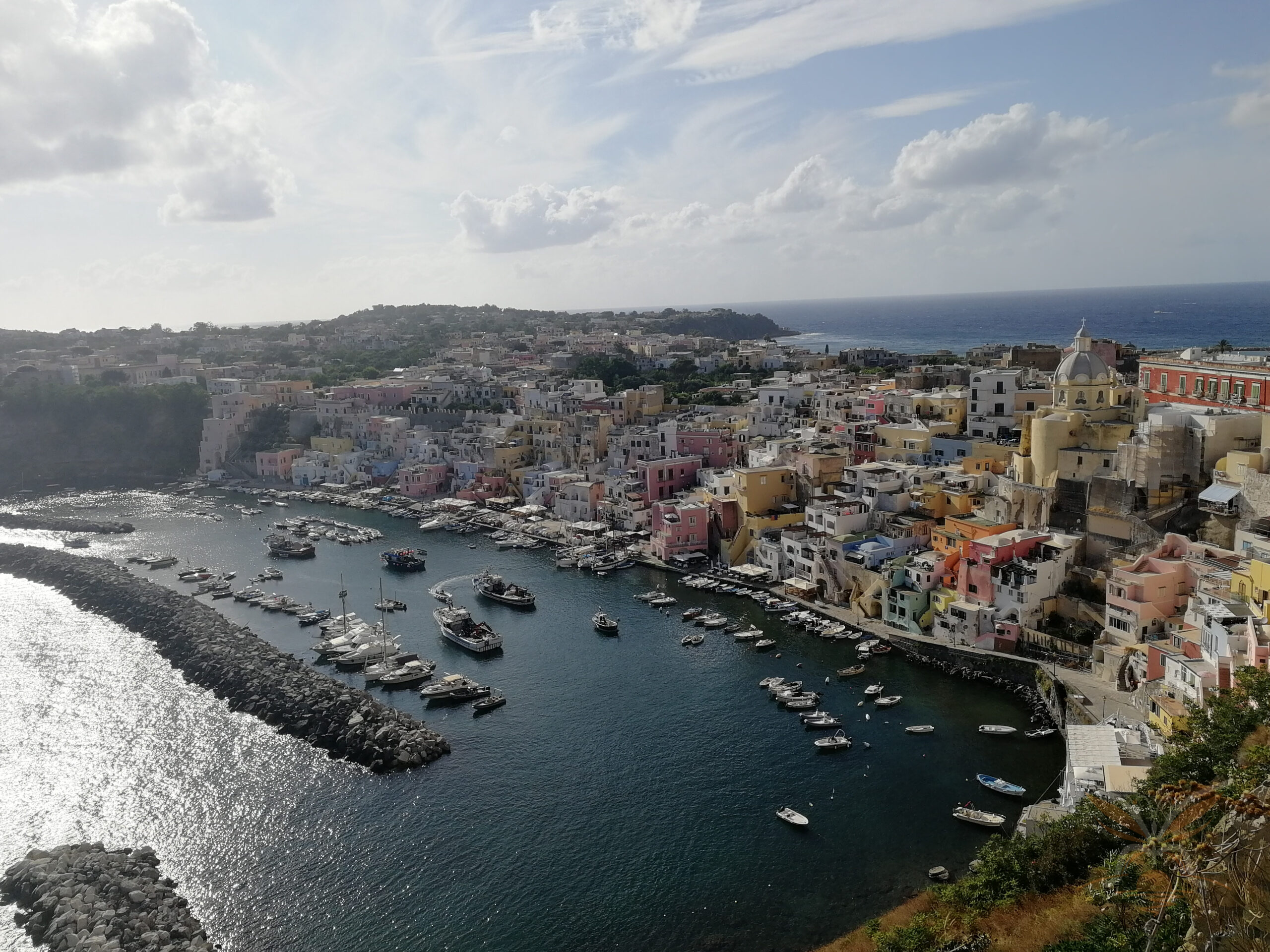 Colourful waterfront houses, fishing boats and the domed church of Marina Corricella in Procida.