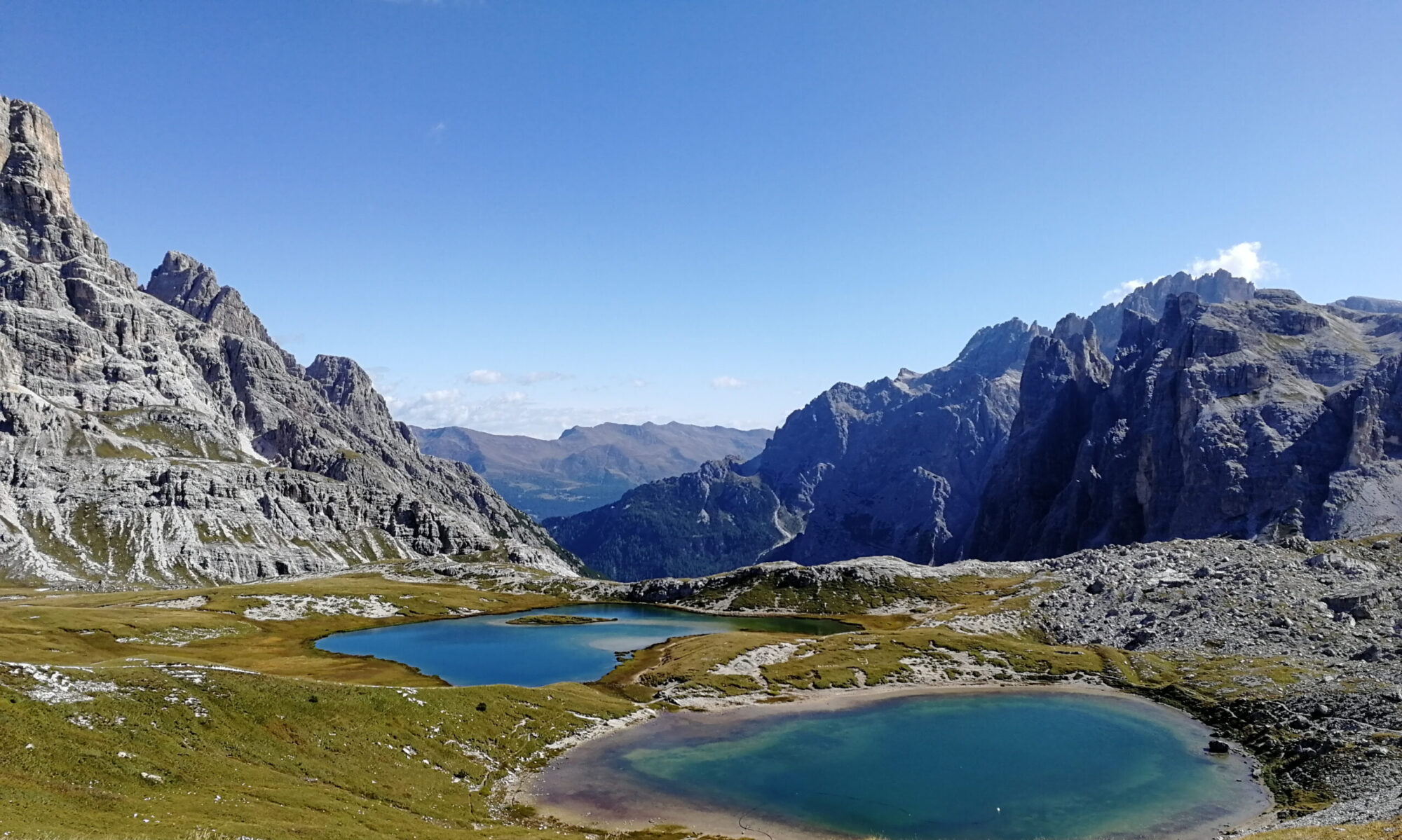 Turquoise alpine lakes surrounded by rugged pale peaks in the Dolomites.