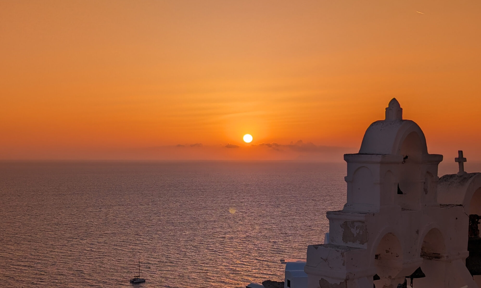 Whitewashed church overlooking the Aegean Sea at sunset in Santorini.