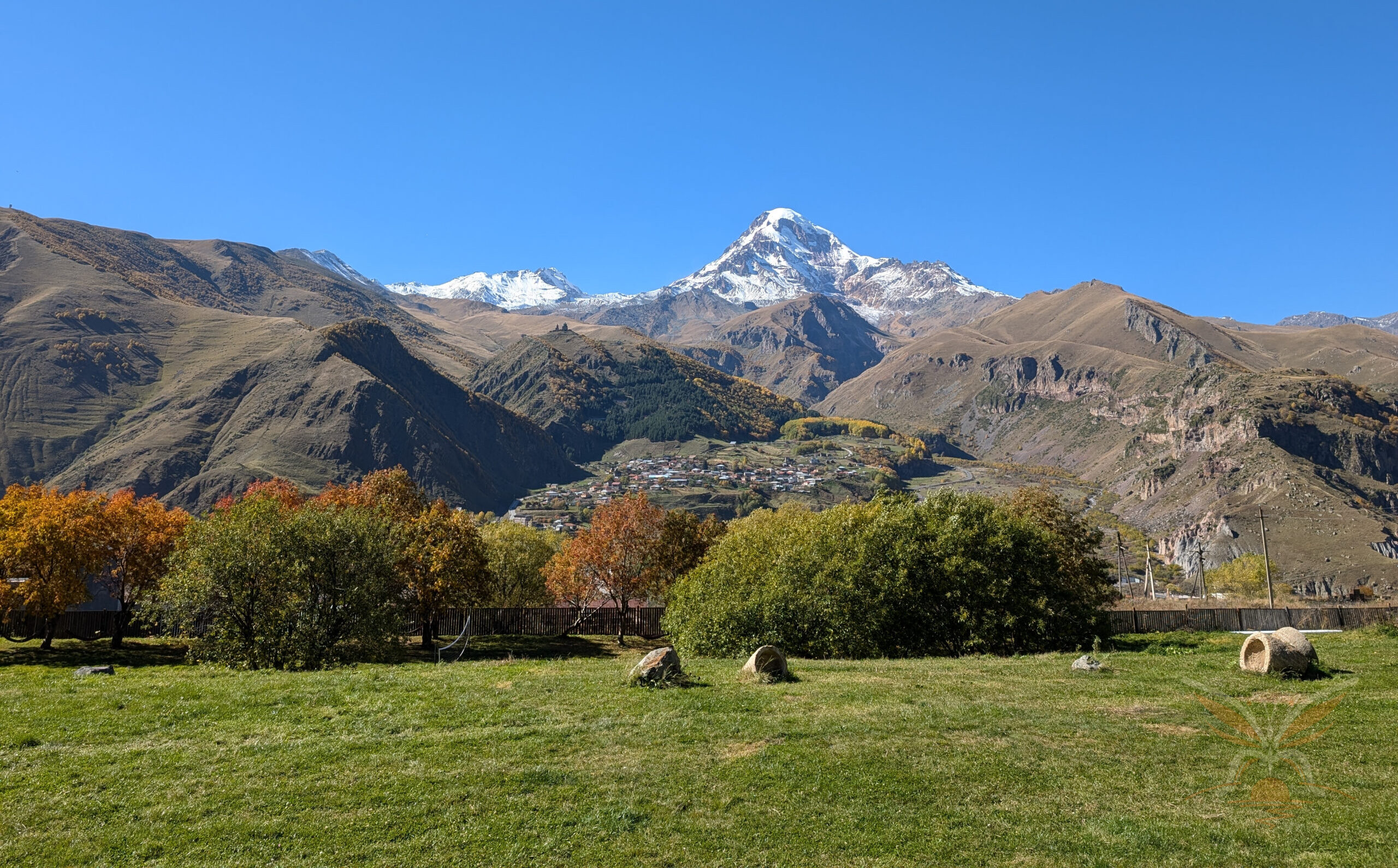 Snow-capped Mount Kazbek rising above Stepantsminda and the autumn-coloured Caucasus landscape.
