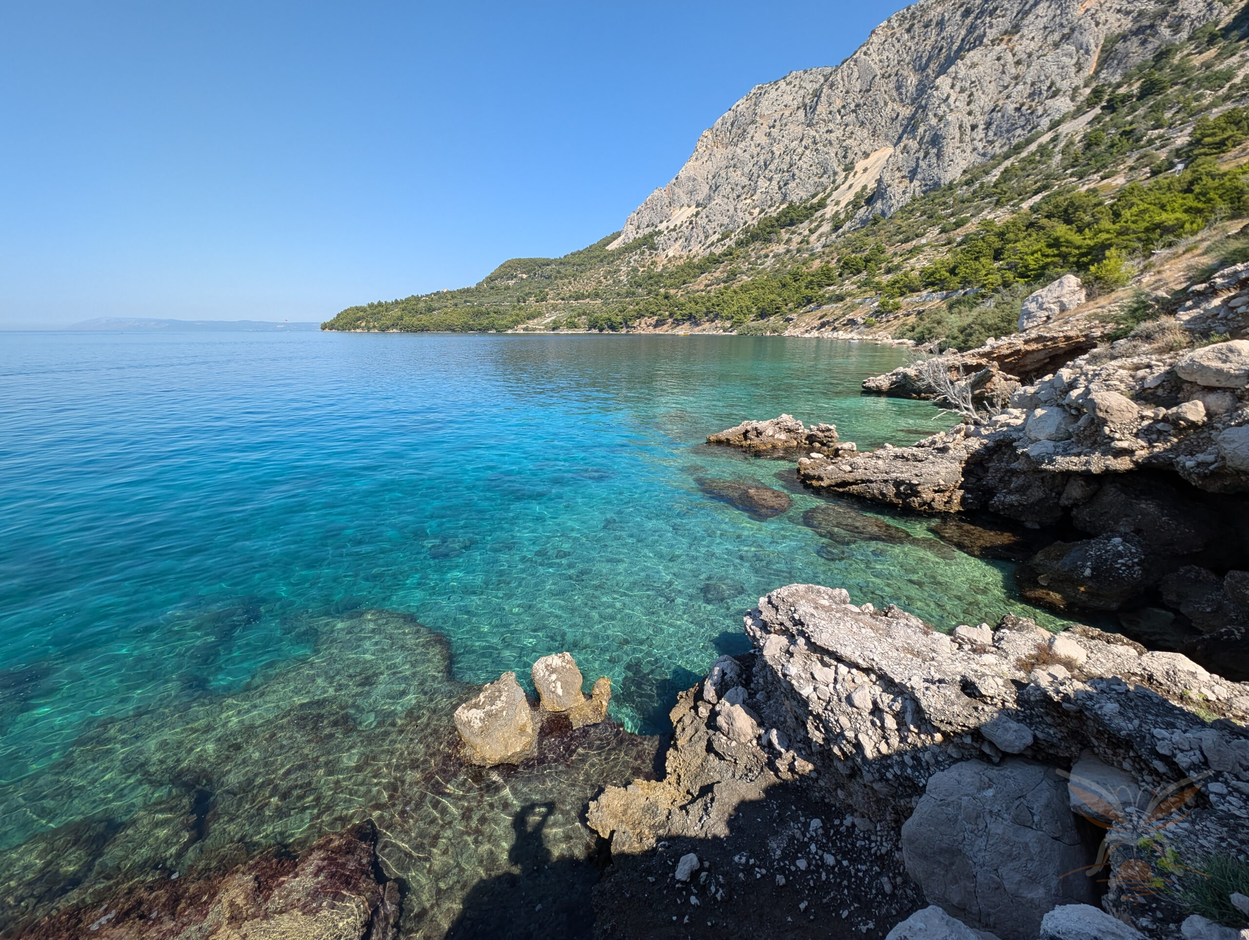 Rocky Adriatic shoreline beneath steep mountain slopes along the Makarska Riviera in Croatia.