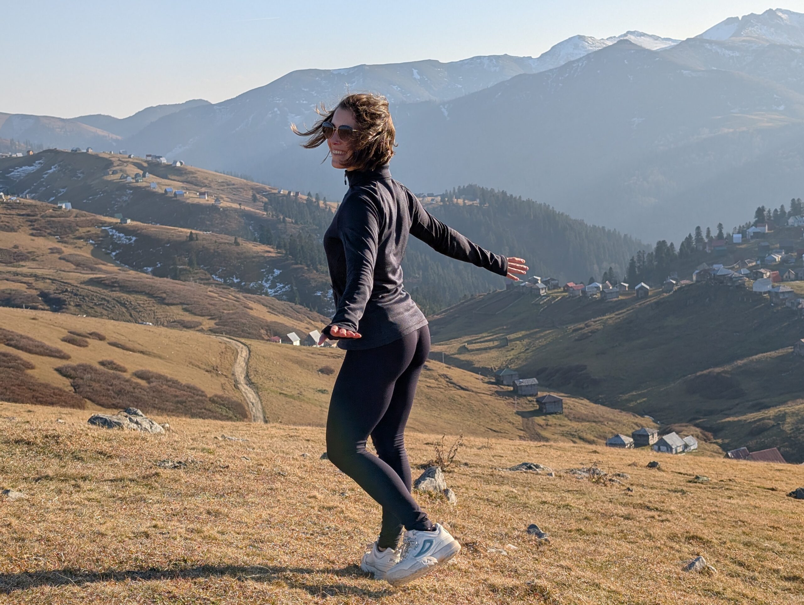 Mariachiara standing on a mountain slope overlooking the scattered houses of Gomismta, Georgia.