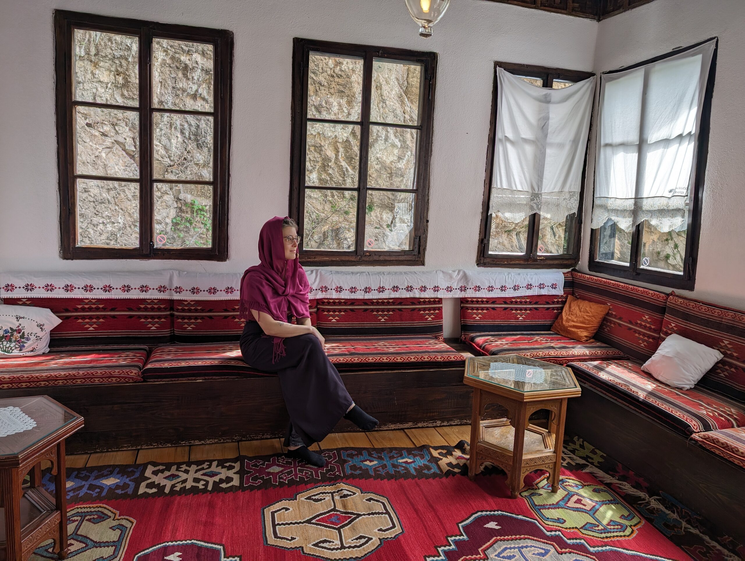 Mariachiara seated in a traditional Bosnian interior with patterned rugs and low wooden seating.