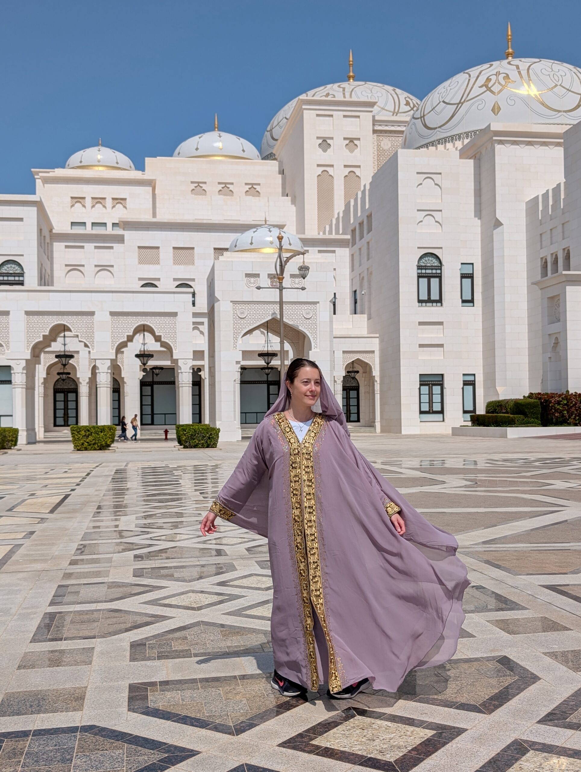 Mariachiara walking through the courtyard of Qasr Al Watan in Abu Dhabi in a flowing lilac outfit.