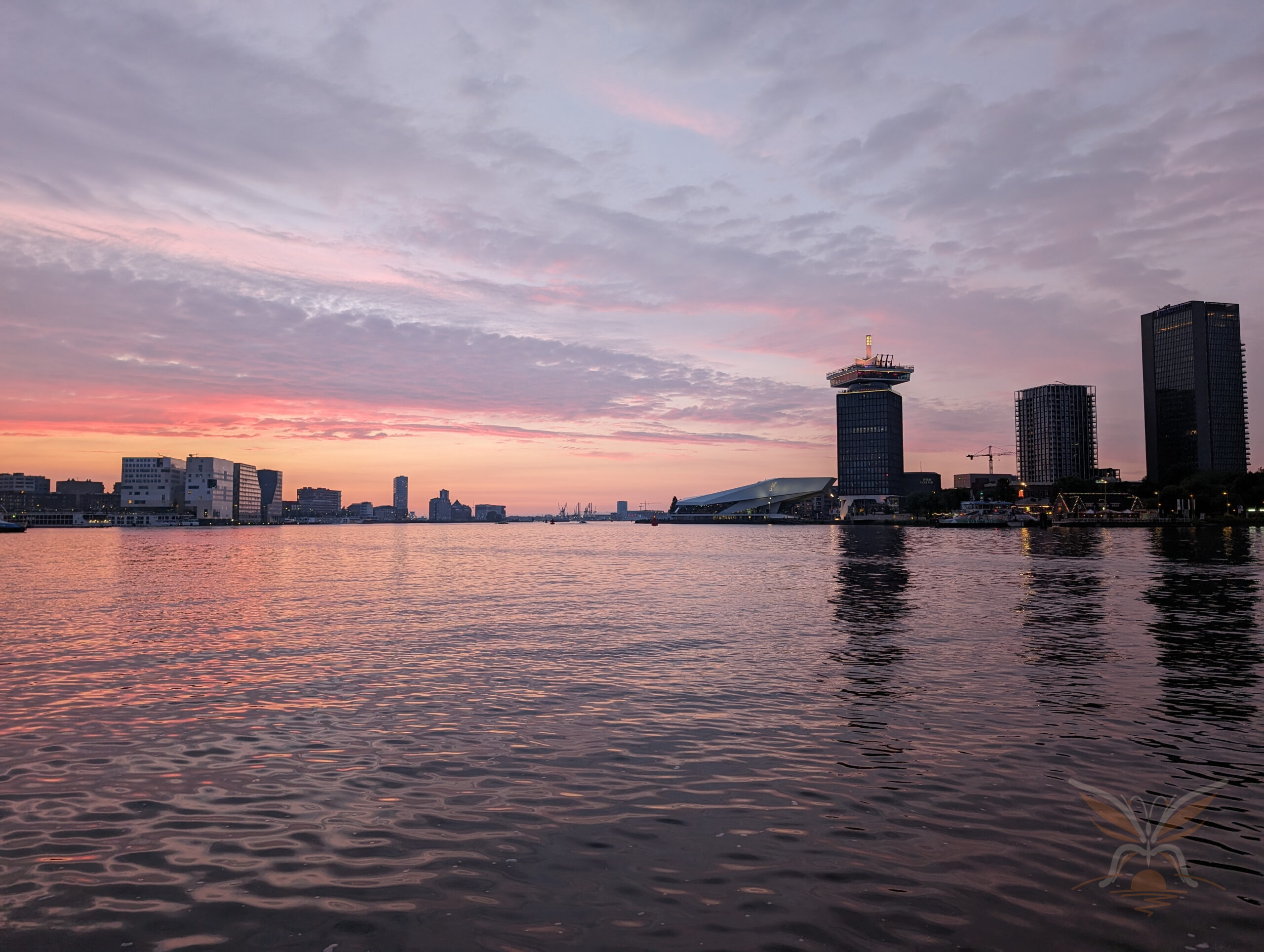 Modern Amsterdam waterfront reflected in the IJ at sunset.