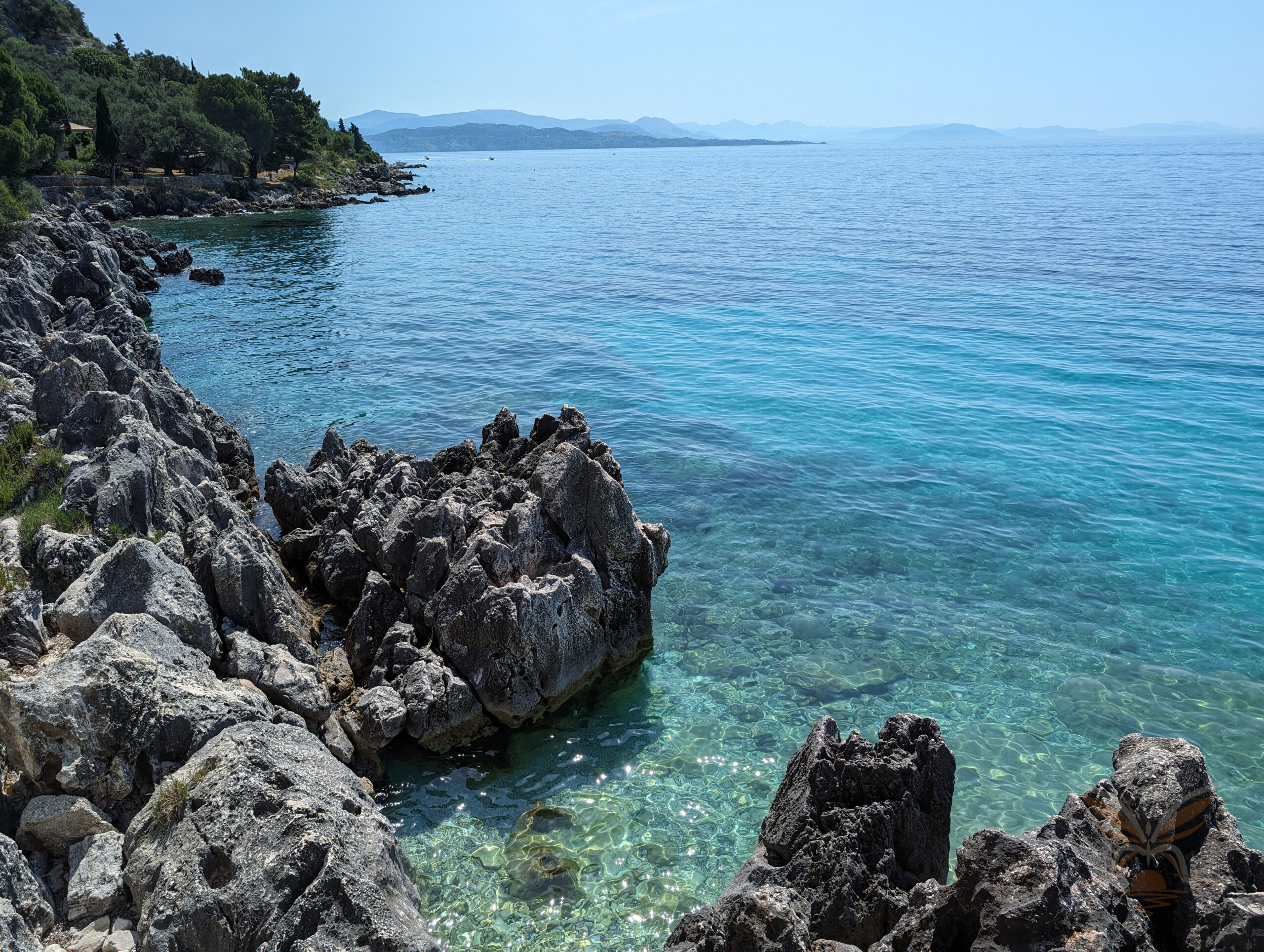 Dark rocks beneath exceptionally clear turquoise water along north-eastern Corfu.