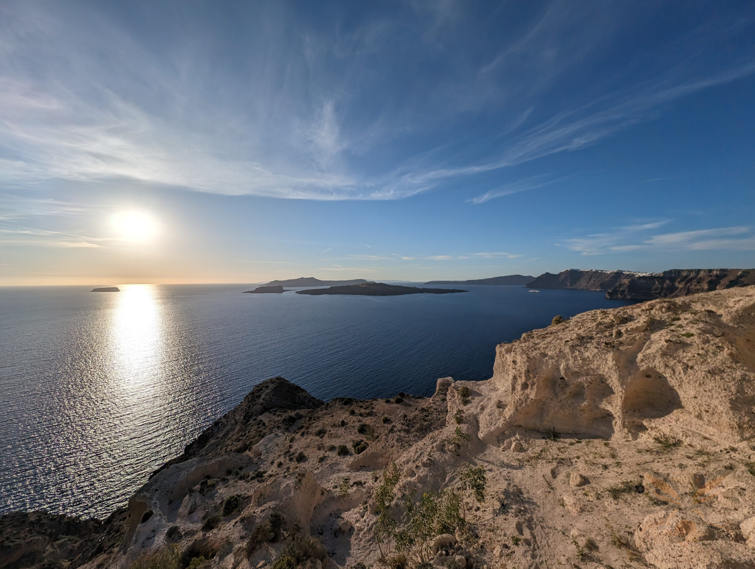Rocky volcanic coastline overlooking the Santorini caldera and Aegean Sea.