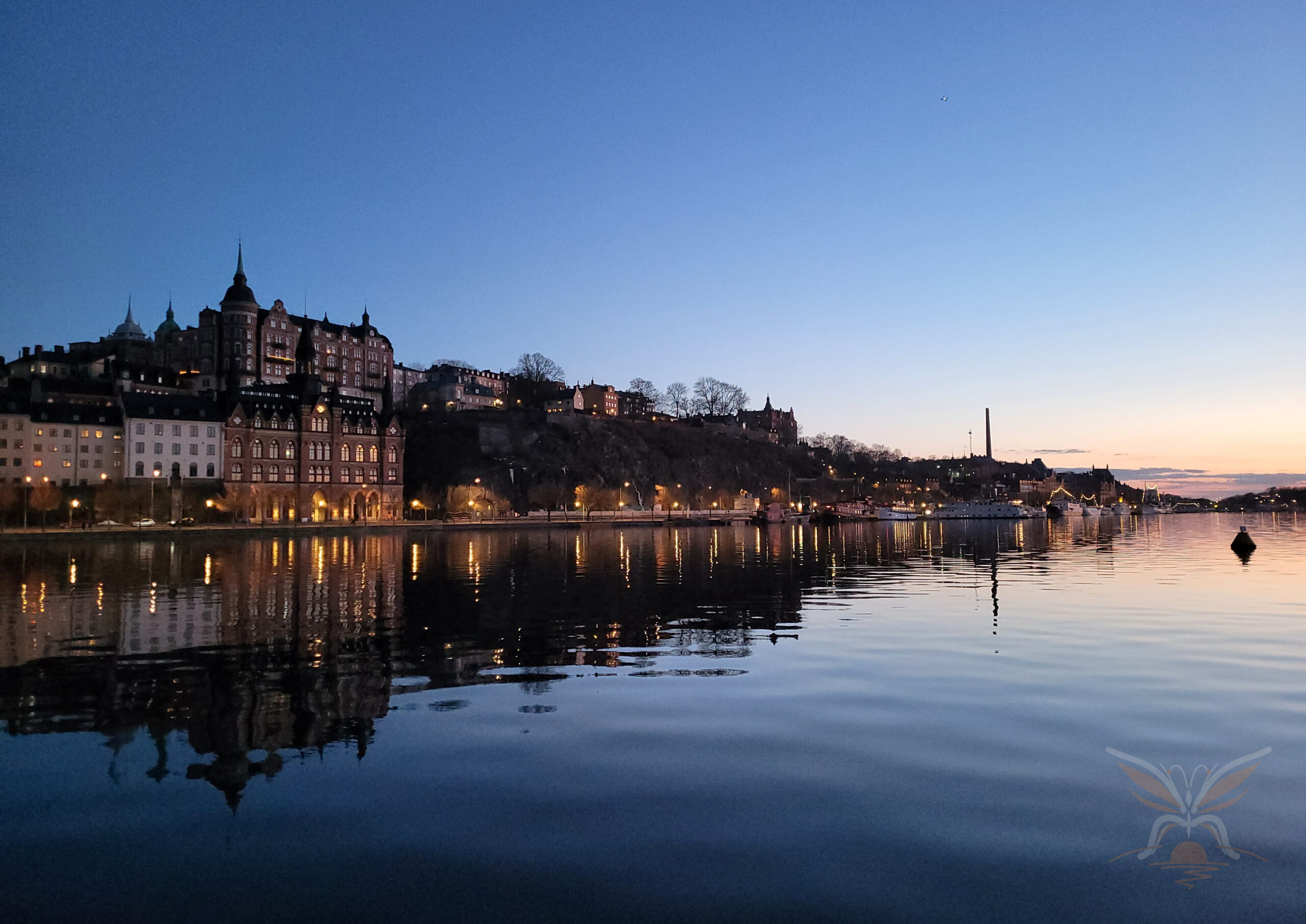 Historic waterfront buildings reflected in calm water after sunset in Stockholm, Sweden.