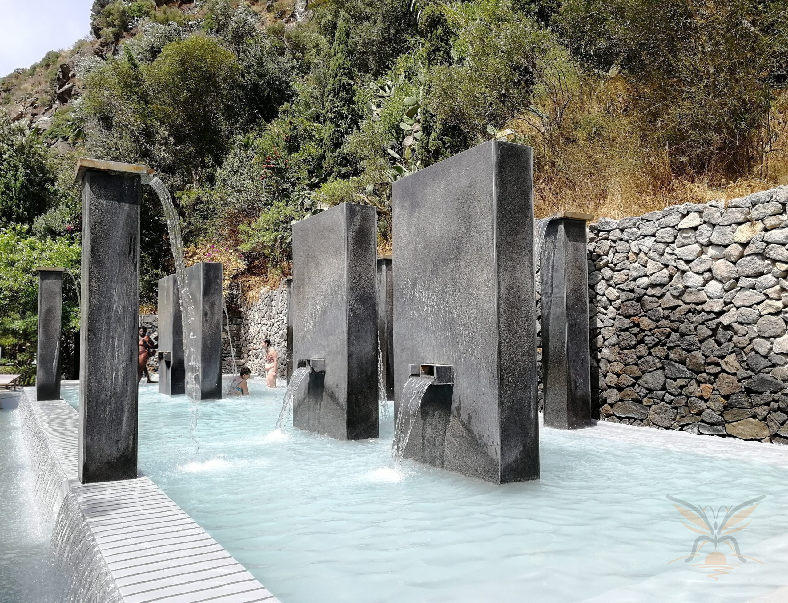 Sculptural thermal installations surrounded by volcanic stone and greenery at Negombo Thermal Park in Ischia.